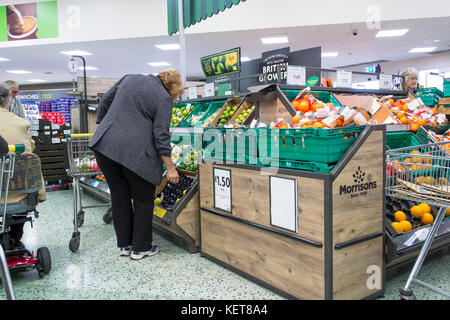 Shopping in un supermercato Morrisons - Un cliente sta guardando la frutta fresca la visualizzazione in un supermercato Morrisons. Foto Stock