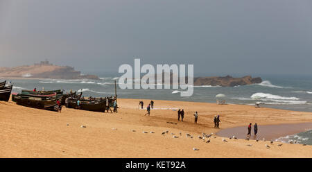 Barche da pesca, i pescatori e i gabbiani su una spiaggia vicino a oualidia, Marocco. Foto Stock