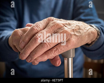 Old mans mani appoggiate sul bastone. Foto Stock