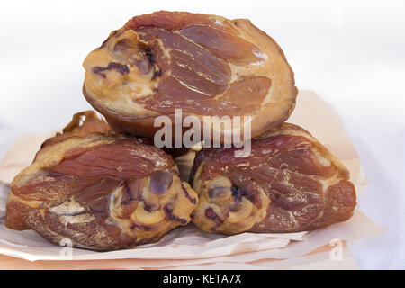 Tre prosciutto affumicato hock su carta in macelleria Foto Stock