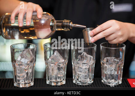 Un barman / bar lavoratore versa a colpi di alcolici in un bar pub. Foto Stock