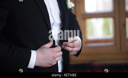 Uomo che abbotta su una giacca nera. Dettagli per matrimoni - l'elegante costume da smoking nuziale con abito da sposo attende la sposa. giacca da abbottonatura uomo d'affari Foto Stock