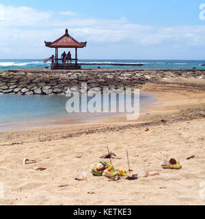 Tropicale idilliaco sabbia spiaggia di Nusa Dua, Bali, Indonesia. stile balinese tradizionale offerte per gli dèi di Bali con fiori e bastoncini aromatici. Foto Stock