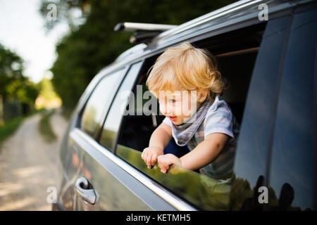 Little Boy giocando in auto, proteso al di fuori della finestra. Foto Stock