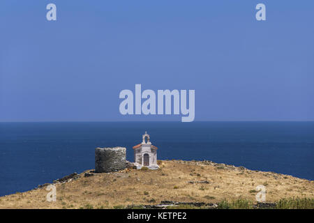 Corthi, tradizionale mulino in pietra e la chiesa bianca nell'isola di Andros, Cicladi Grecia Foto Stock