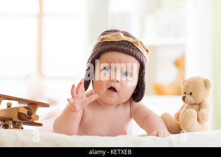 Funny baby boy usurata cappello pilota con velivoli in legno e orso di peluche giocattoli Foto Stock