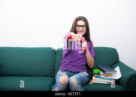 Felice college girl prendendo una pausa dalla lettura e facendo esercizi in salotto Foto Stock