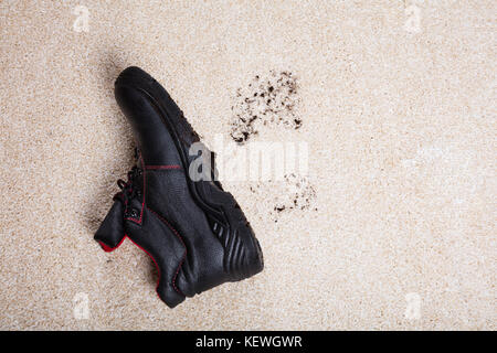 Elevato angolo di visione di un paio di scarpe con il fango sdraiato sul pavimento moquette Foto Stock