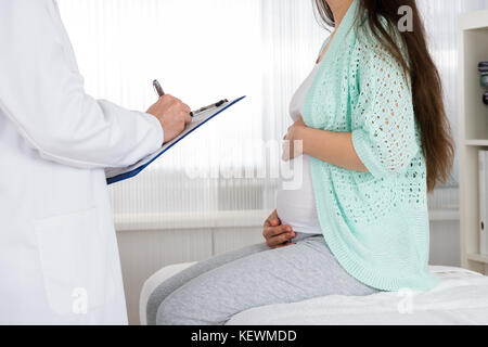 Medico dando la prescrizione a donne in stato di gravidanza della donna in ospedale Foto Stock