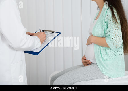 Medico dando la prescrizione a donne in stato di gravidanza della donna in ospedale Foto Stock