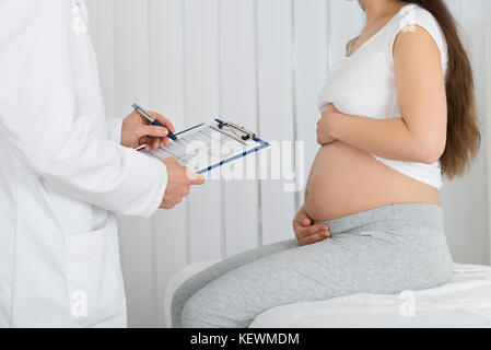 Medico dando la prescrizione ad aspettarsi la donna in ospedale Foto Stock