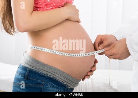 Close-up medico di controllare la crescita del bambino con nastro di misurazione in clinica Foto Stock