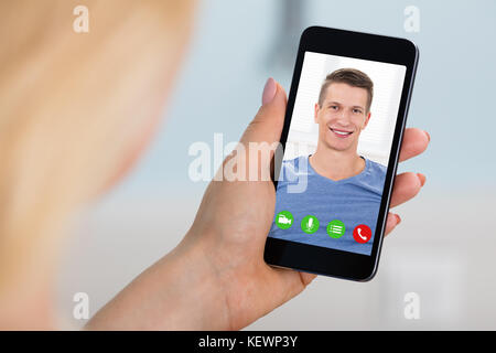 Close-up di donna la videoconferenza con uomo su mobilephone. online dating concept Foto Stock