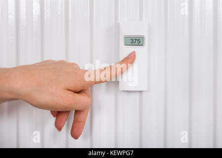 Close-up di persona la mano la regolazione della temperatura con termostato digitale Foto Stock