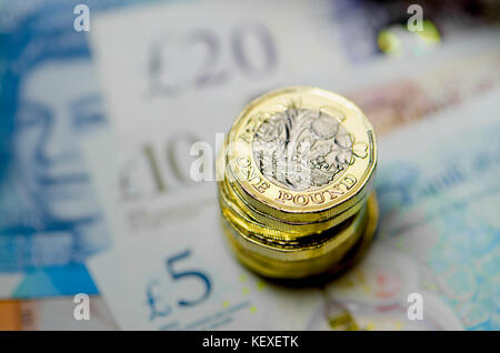 Valuta britannica - pila di nuovo (2016) pound monete su £5 £10, £20 note Foto Stock