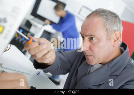 Maschio macchinista tecnico lavoratore regolazione meccanismo di ascensore Foto Stock