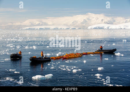 I membri di una crociera spedizione in Antartide in un Zodiak con il kayak da mare in Fournier Bay in stretto di Gerlache sulla penisola antartica. La penisola antartica è uno dei più rapidamente le aree di riscaldamento del pianeta. Foto Stock