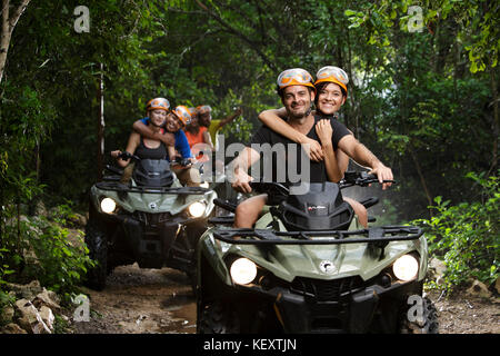 Le coppie che abbraccia mentre cavalcate quad bikes in emozioni Parco nativo, Quintana Roo, Messico Foto Stock