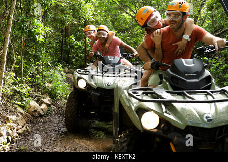 Le coppie che abbraccia mentre cavalcate quad bikes in emozioni Parco nativo, Quintana Roo, Messico Foto Stock