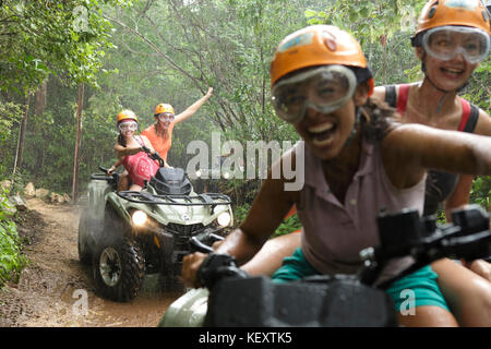 Le donne ridere mentre si guida quad bikes in emozioni Parco nativa durante la pioggia, Quintana Roo, Messico Foto Stock