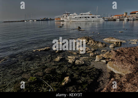 Rocce sulla riva e ormeggiate imbarcazioni da diporto nel Porto di Paphos nel mare Mediterraneo, Cipro, europa Foto Stock