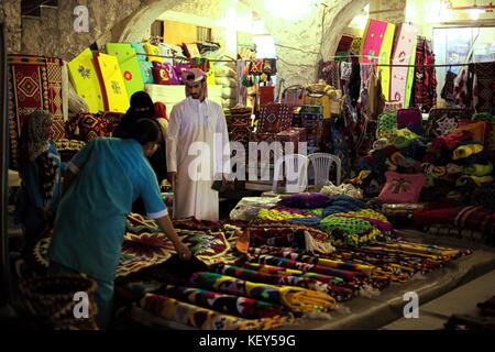 Doha, Qatar - 23 aprile 2017: gli acquirenti acquisto tessuti nel souq waqif market in Qatar Arabia, di notte Foto Stock