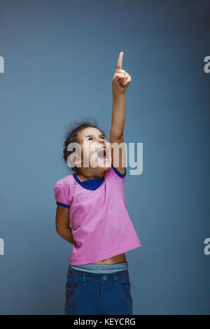 La ragazza ha sollevato il suo pollice alzato grida su sfondo grigio Foto Stock