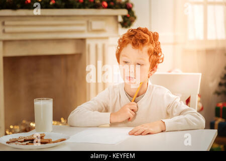 Malinconici boy lottando con la lettera a Babbo Natale Foto Stock