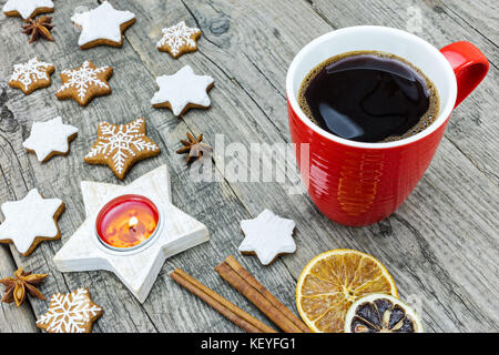 Iced star cookies con candela accesa, cannella, fette di arancia e la tazza di caffè su sfondo grigio Foto Stock