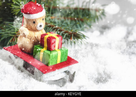 Albero di natale giocattolo, piccolo orso sembrava babbo natale,su slitte. Buon Natale biglietto di auguri con la neve sullo sfondo. spazio copia Foto Stock