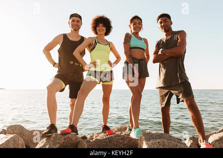 Gruppo di fitness felici le persone che posano su pietre dopo la formazione e guardando la telecamera Foto Stock