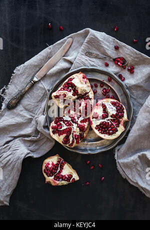 Rosso maturo pelato melograno rustico sulla piastra di metallo e beige asciugamano da cucina Foto Stock