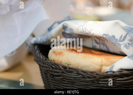 Round di pane bianco in un cestino sotto il panno blu Foto Stock