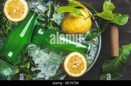 Bottiglie di limonata verde su scaglie di ghiaccio nel vassoio di metallo Foto Stock