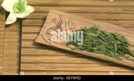 Teiera di vetro con fiore di tè in fiore all'interno su sfondo in legno foglie di tè verde cinese da vicino in tazza tradizionale. cerimonia del tè. Tè cinese, cerimonia Foto Stock
