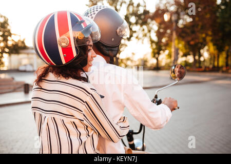 Vista posteriore del giovane africano corse su moto moderne in posizione di parcheggio Foto Stock