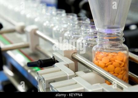 Industria farmaceutica, medicina pillole sono il riempimento della bottiglia di plastica sulla linea di produzione trasportatore di macchina presso il medico di fabbrica. Il fuoco selettivo. Foto Stock