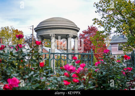 Un monumento di pietra in New Hampshire park si trova sulla cima di un piccolo giardino con fiori luminosi. Foto Stock