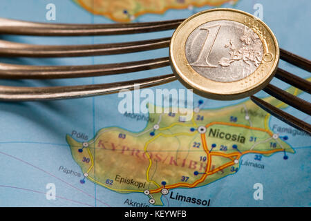 Due Forcelle tenere una moneta in euro di Cipro sulla mappa. Foto Stock