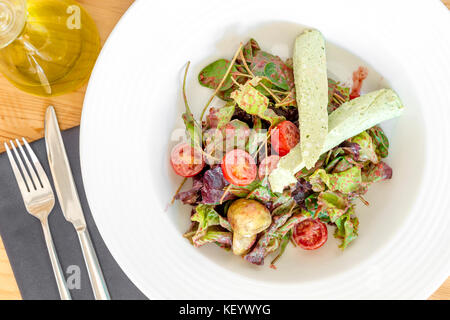 Insalata con patè di formaggio con spezie, baby spinaci, pomodori ciliegini, lattuga e condimento. Foto Stock