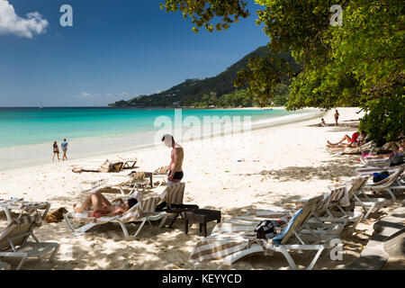 La Seychelles, Mahe, Beau Vallon, spiaggia, turisti rilassante accanto al mare sulle sedie a sdraio Foto Stock