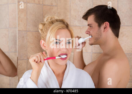 Ritratto di un uomo e di una donna spazzolare i denti in bagno a casa Foto Stock