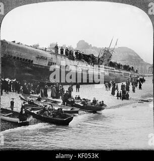 HASTINGS, EAST SUSSEX. Persone in imbarcazioni a remi e sulla spiaggia, guardando le U-boat tedesca sottomarino, U-118, che si è arenata sulla spiaggia di Hastings Foto Stock