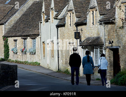 Tre turisti asiatici ad esplorare il villaggio di Castle Combe, Wiltshire, Inghilterra, Regno Unito Foto Stock