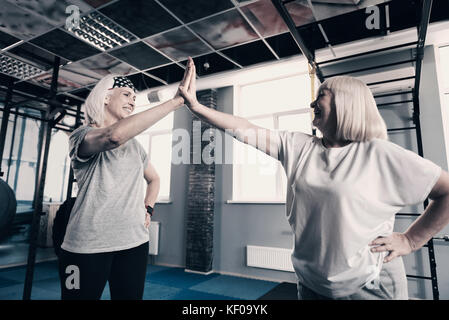 Due donne senior high-fiving ogni altro in palestra Foto Stock