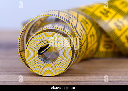 Vicino la vista dettagliata del nastro giallo misurare su sfondo di legno. Foto Stock