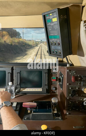 Vista interna di una cabina per il conducente di un treno in movimento con più pannelli e pulsanti come un uomo con un orologio regolare una leva Foto Stock