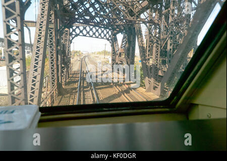 Vista di un ponte con binari del treno su un fiume attraverso una finestra del treno o di un locomotore finestra motore Foto Stock