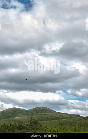 Grandi nuvoloso natura paesaggio con sole nascosto dietro le nuvole e piccolo giallo aereo in background Foto Stock