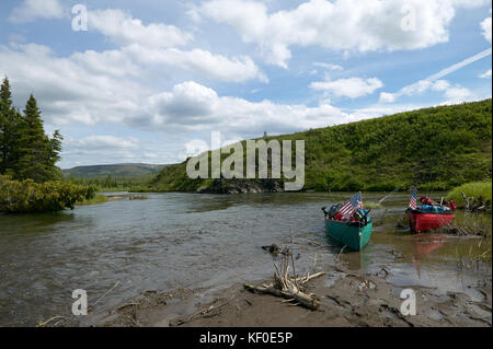 Due spiaggiata canoe su un telecomando, scenic alaskan banca di fiume con una soleggiata cielo blu. Foto Stock